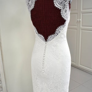 Puede incluir: Un vestido de novia de encaje blanco con la espalda baja y una fila de botones en la espalda.