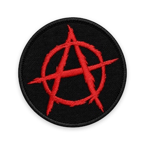 Könnte beinhalten: Ein kreisförmiger bestickter Aufnäher mit schwarzem Hintergrund und einem leuchtend roten Anarchie-Symbol in der Mitte. Das Design besteht aus einem großen Buchstaben A, der von einem Kreis umschlossen ist, wobei der rote Faden eine Textur erzeugt.