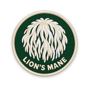 May include: A circular embroidered patch featuring a dark green background with a cream-coloured border. The centre displays a white and cream-coloured graphic of a lion's mane mushroom. The text LION'S MANE is embroidered in cream below the graphic.