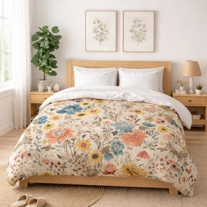 Peut inclure: Chambre à coucher avec un lit en bois recouvert d'une housse de couette à motifs floraux jaunes, bleus et oranges. Deux oreillers blancs sont visibles. La pièce comprend deux tables de chevet, une suspension en osier et des estampes botaniques encadrées.