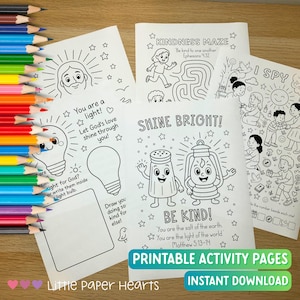 May include: A collection of printable activity pages with black line drawings and text, including mazes, I Spy games, and inspirational messages. The pages feature illustrations of a lightbulb, salt shaker, and lantern. Colored pencils are visible in the background.