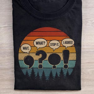 Może przedstawiać: Czarny t-shirt z okrągłym dekoltem i okrągłą grafiką przedstawiającą zachód słońca w stylu retro z pomarańczowymi, żółtymi i turkusowymi paskami nad sylwetką lasu. Wzór zawiera cztery dymki z tekstem WAIT, WHAT, STOP IT, I AGREE.