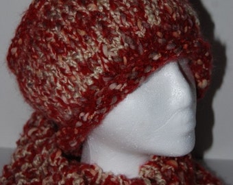 May include: A hand-knitted beanie hat and matching scarf set crafted from thick, textured red and beige pebbles yarn. The set features a chunky knit pattern with a variegated color blend, displayed on a white mannequin head and neck form.