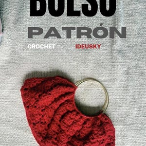 Puede incluir: Un bolso de ganchillo rojo con un asa circular de metal dorado. El texto BOLSO PATRÓN CROCHET IDEUSKY está impreso en negro y gris sobre el bolso. El fondo es una superficie texturizada de color gris claro con una pequeña bandera española.