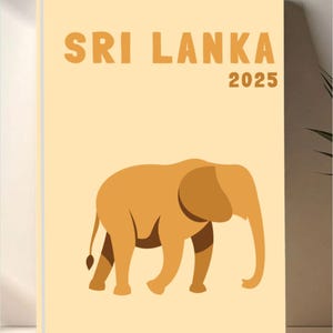 May include: A tan-colored notebook with the words "SRI LANKA 2025" in orange lettering. A stylized elephant illustration in shades of brown is featured on the cover. The notebook is likely a travel journal or planner.