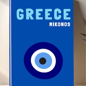 May include: A blue rectangular print with the word "GREECE" in light blue above "MIKONOS" in white. A blue and white eye symbol is at the bottom. The print is likely for wall decor.