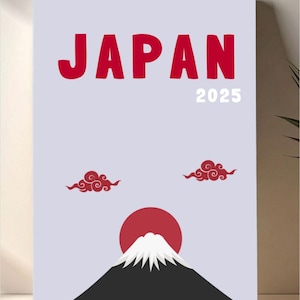 May include: A rectangular print featuring the word "JAPAN" in red, with the year "2025" in white. The design includes a red sun, a black mountain with a white peak, and two red cloud motifs against a light blue background.