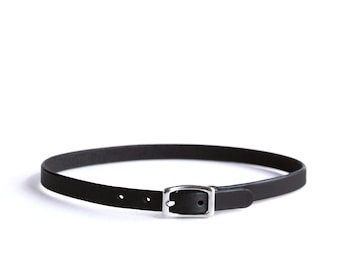 May include: A thin black leather belt featuring a smooth matte finish and a rectangular silver-toned metal buckle. The belt strap has two visible adjustment holes near the buckle, which is secured with a single metal prong.