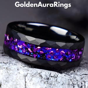 May include: Black ring with a hammered texture and a vibrant inlay of purple and blue crushed stone. The ring is set against a neutral background, with the text "GoldenAuraRings" at the top.