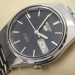 Reloj automático vintage Seiko 5 para hombre, esfera negra, caja de 34,9 mm, fondo transparente.