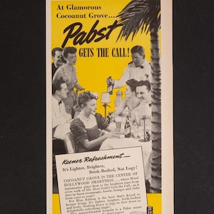 May include: A vintage advert for Pabst Blue Ribbon beer. The image shows people socialising with drinks, with the text "Pabst Gets The Call!" and "Perk-up with Pabst Blue Ribbon." The background is yellow.
