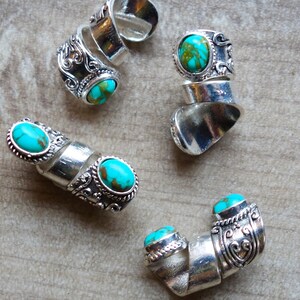 May include: Four silver rings with turquoise stones. The rings are adjustable and have a spiral design.