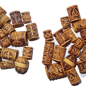 May include: A collection of wooden hair beads with intricate carvings. The beads are brown and beige with a variety of patterns, including geometric designs and symbols.