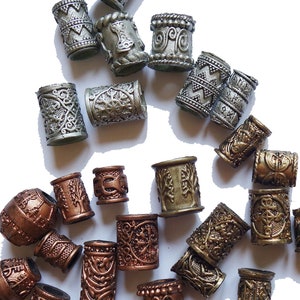 May include: A collection of decorative hair beads in silver, gold, and copper tones. The beads are cylindrical and feature intricate designs.