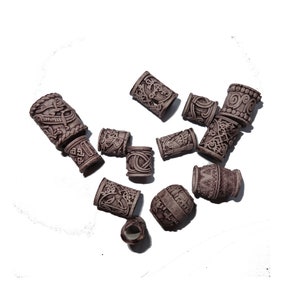 May include: A collection of 11 brown hair beads with intricate designs. The beads are made of a textured material and have a slightly raised surface.