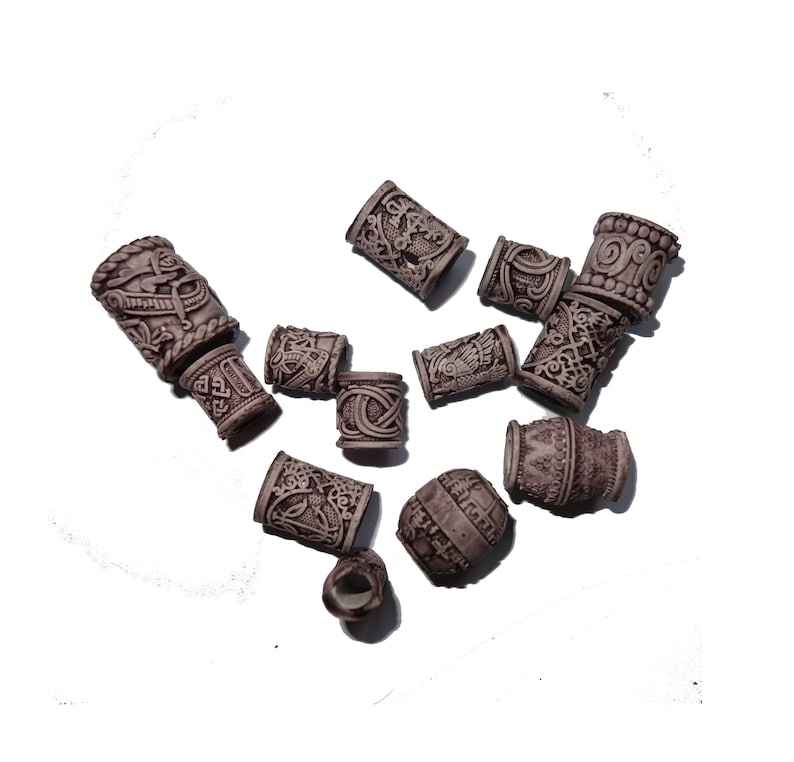 May include: A collection of 11 brown hair beads with intricate designs. The beads are made of a textured material and have a slightly raised surface.