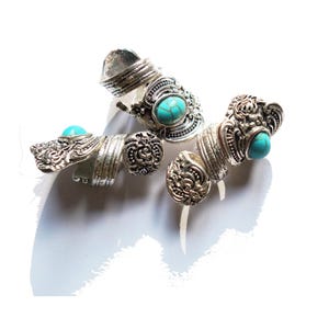 May include: Three silver rings with turquoise stones. The rings are ornate and have a vintage style.