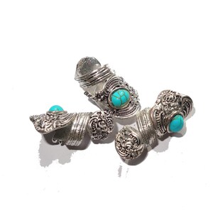 May include: Three silver rings with turquoise stones. The rings are ornate and have a spiral design.