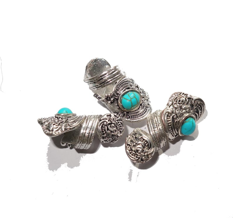 May include: Three silver rings with turquoise stones. The rings are ornate and have a spiral design.