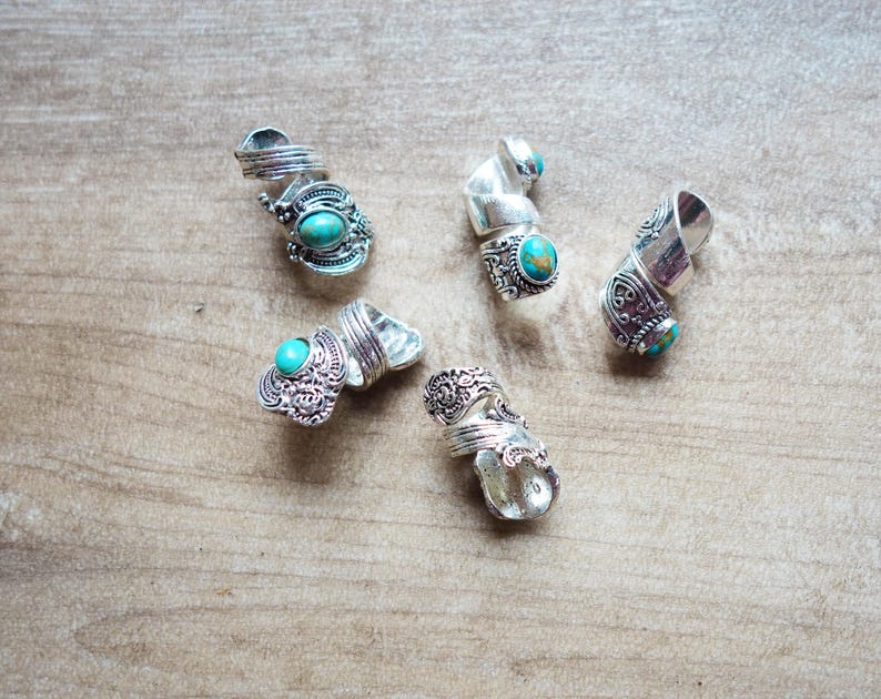 May include: Five silver rings with turquoise stones. The rings are ornate and have a spiral design.