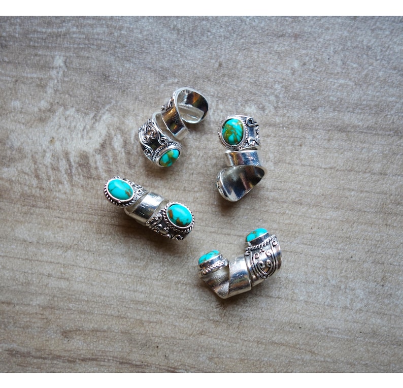 May include: Four silver rings with turquoise stones. The rings are adjustable and have a spiral design.