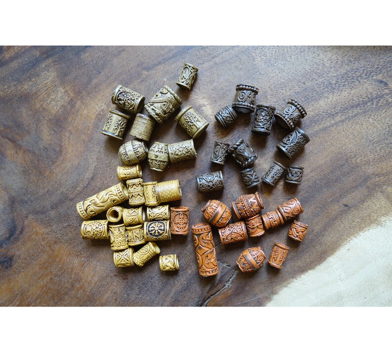 May include: A collection of wooden hair beads with intricate designs. The beads are in three colors: brown, tan, and orange. The beads are arranged in a random pattern on a wooden surface.