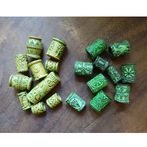 May include: A collection of green and yellow hair beads with intricate designs. The beads are made of plastic and have a glossy finish.