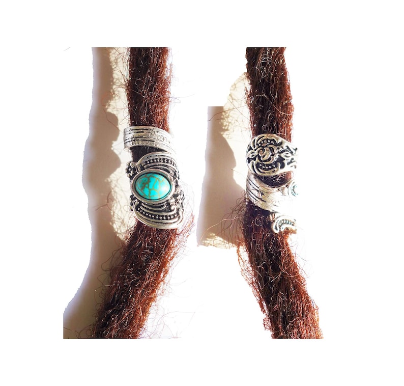 May include: Two silver dreadlock beads with turquoise stones. The beads are ornate and have a floral design.