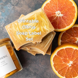 Puede incluir: Una pila de jabones con aroma cítrico con un patrón amarillo y blanco en espiral, junto con rodajas de naranja. También se ve un frasco de especia de cúrcuma. Se muestra el texto "Printable Citrus Soap Label Set".