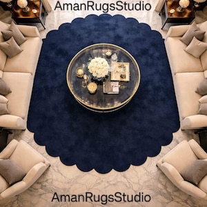 Puede incluir: Vista aérea de un salón con una alfombra azul marino con volantes. Dos sofás seccionales color crema y dos sillones rodean la alfombra. Una mesa de centro redonda con borde dorado se encuentra en el centro, con objetos decorativos.