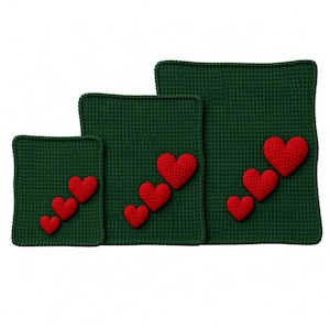 May include: Three square dark green crocheted mats of varying sizes, each featuring a diagonal row of three red crocheted hearts attached to the surface. The hearts increase in size proportionally with each of the three dark green mats.