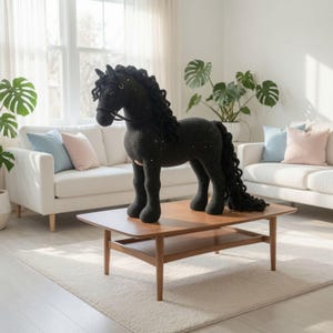 May include: A large, black crocheted horse figurine featuring a textured mane and tail with long, curly strands. The horse has a simple bridle detail around its head and a solid, dark body construction, standing upright on four sturdy legs.