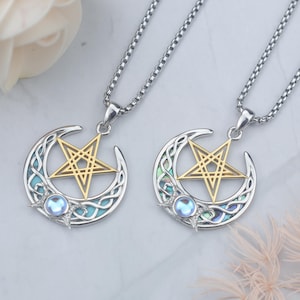May include: Two silver necklaces with pendants featuring a gold pentagram within a crescent moon design. The moon has an abalone inlay and a small blue gemstone. The necklaces are on a silver chain.