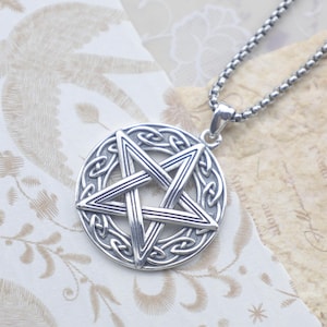 May include: A silver-colored pendant necklace featuring a pentagram within a circular Celtic knot design. The pendant hangs from a matching silver chain. The necklace is displayed on a patterned background.