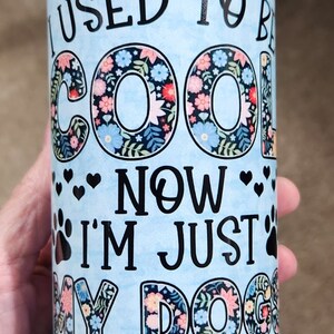 Könnte beinhalten: Ein hellblauer Becher mit einem Blumenmuster und dem Text "Ich war cool, jetzt bin ich nur noch der Snack-Dealer meines Hundes".