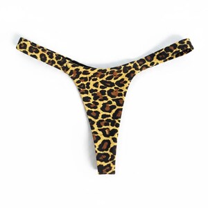 May include: A thong-style bottom with a leopard print pattern. The underwear features a tan background with brown spots. The garment is made of a soft, stretchy material.