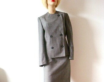 May include: A gray and black double-breasted blazer and skirt suit with a white fur hat.