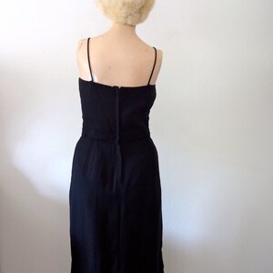 May include: A black sleeveless dress with a fitted bodice and a straight skirt. The dress is made of a smooth, silky fabric.