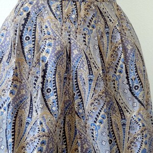 May include: A pleated skirt with a paisley pattern in shades of blue, brown, and white.