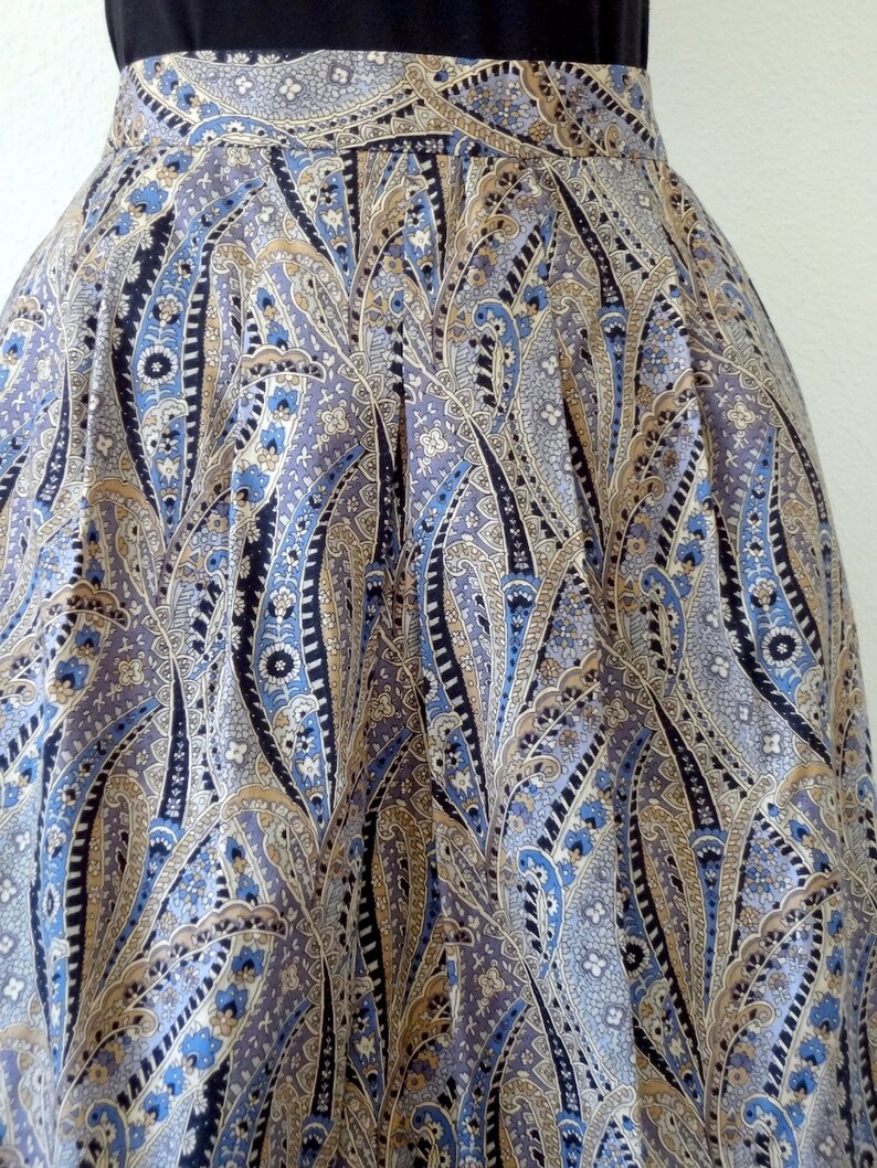 May include: A pleated skirt with a paisley pattern in shades of blue, brown, and white.