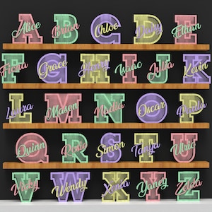 May include: A display of colorful, illuminated letters spelling out names, arranged on wooden shelves against a dark background. Each letter is a different pastel color, with the names written in a cursive font.