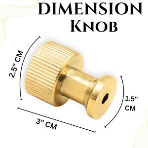 Pode incluir: Um puxador de lat&atilde;o com o texto "DIMENSION KNOB". O puxador tem 7,6 cm de comprimento, 6,4 cm de largura e 3,8 cm de di&acirc;metro. O puxador tem uma textura canelada na parte cil&iacute;ndrica.