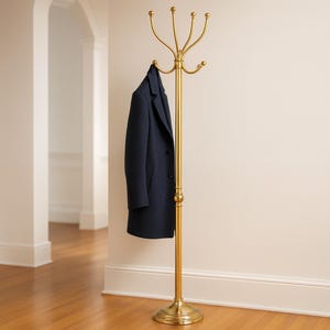 Puede incluir: Un perchero dorado con múltiples ganchos, sosteniendo un abrigo azul marino. El perchero tiene una base redonda y un poste alto y delgado con brazos curvos en la parte superior. El fondo presenta una pared de color claro y suelo de madera.
