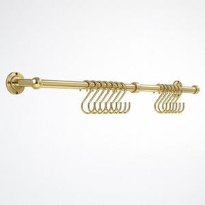 May include: A gold-colored metal hanging rack with multiple S-shaped hooks. The rack is mounted on a wall and has a cylindrical bar with two sets of hooks. The design is simple and elegant, suitable for organizing items.