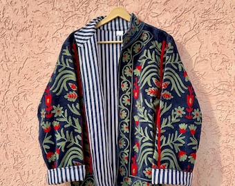 Könnte beinhalten: Eine dunkelblaue Jacke mit aufwendigen Blumenstickereien in Grün- und Rottönen. Das Kleidungsstück hat einen Stehkragen, lange Ärmel mit umgeschlagenen Manschetten und ein Innenfutter mit vertikalem weiß-dunkelblauem Streifenmuster.