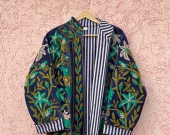 Könnte beinhalten: Eine dunkelblaue Jacke mit leuchtend grüner und rosafarbener Blumenstickerei auf den Ärmeln und Vorderteilen. Das Kleidungsstück hat einen Stehkragen, lange Ärmel mit gestreiften Bündchen und ein kontrastierendes Innenfutter mit vertikalen Streifen.