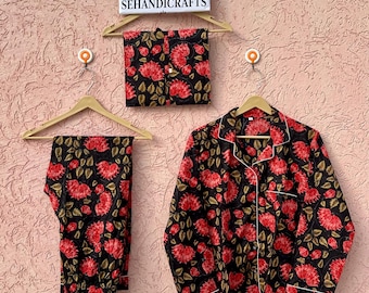 Könnte beinhalten: Ein schwarzer Schlafanzug mit einem leuchtend roten Blumenmuster und grünen Blättern. Das Set besteht aus einem langärmeligen Hemd mit Knopfleiste und weißer Paspelierung sowie einer passenden Hose. Ein Schild zeigt ETSY SHOP SEHANDICRAFTS.