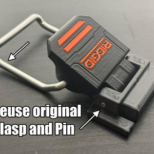 Puede incluir: Pieza de repuesto impresa en 3D en negro y naranja con la palabra "RIDGID" en naranja. Se adjunta un cierre de metal plateado. El texto "Reuse original Clasp and Pin" est&aacute; en la imagen. Esta es una pieza de repuesto para herramientas.