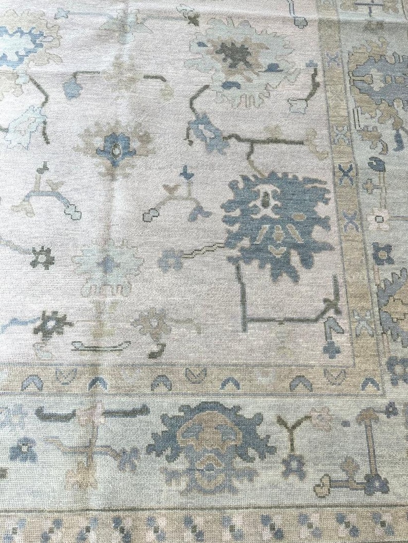 K&ouml;nnte beinhalten: Hellgrauer Teppich mit detailliertem Blumenmuster in Blau-, Beige- und Gr&uuml;nt&ouml;nen. Der Teppich hat einen verzierten Rand und einen Used-Look im Vintage-Stil, geeignet f&uuml;r Wohn- oder Schlafzimmer.