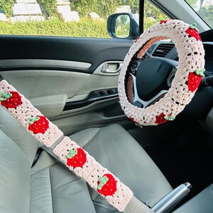 Puede incluir: Juego de accesorios de coche de ganchillo con funda para volante y fundas para cinturón de seguridad. El conjunto es de color crema con aplicaciones de fresas rojas y hojas verdes. Diseñado para el interior de un coche.